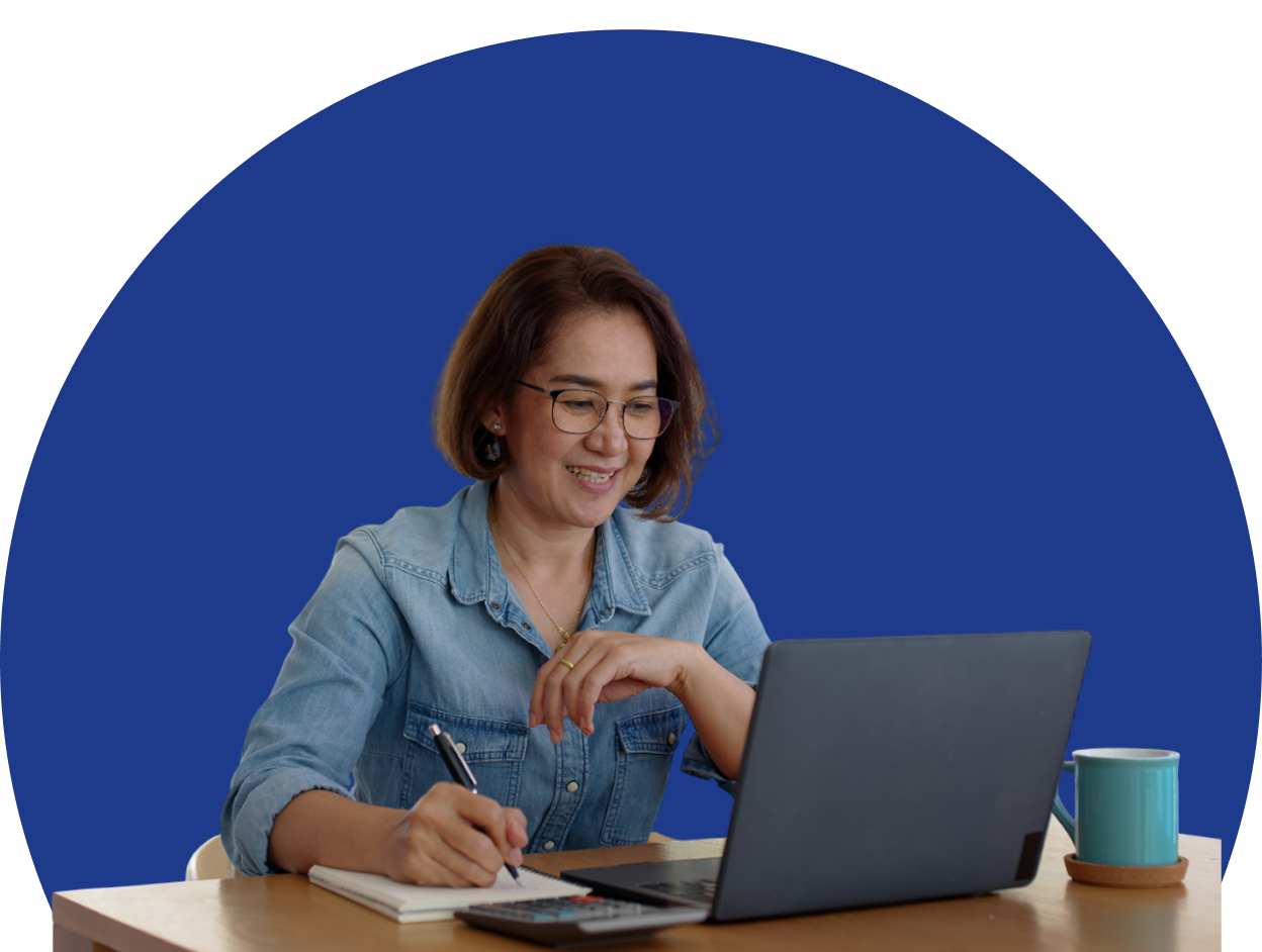 Woman working on laptop with notebook.